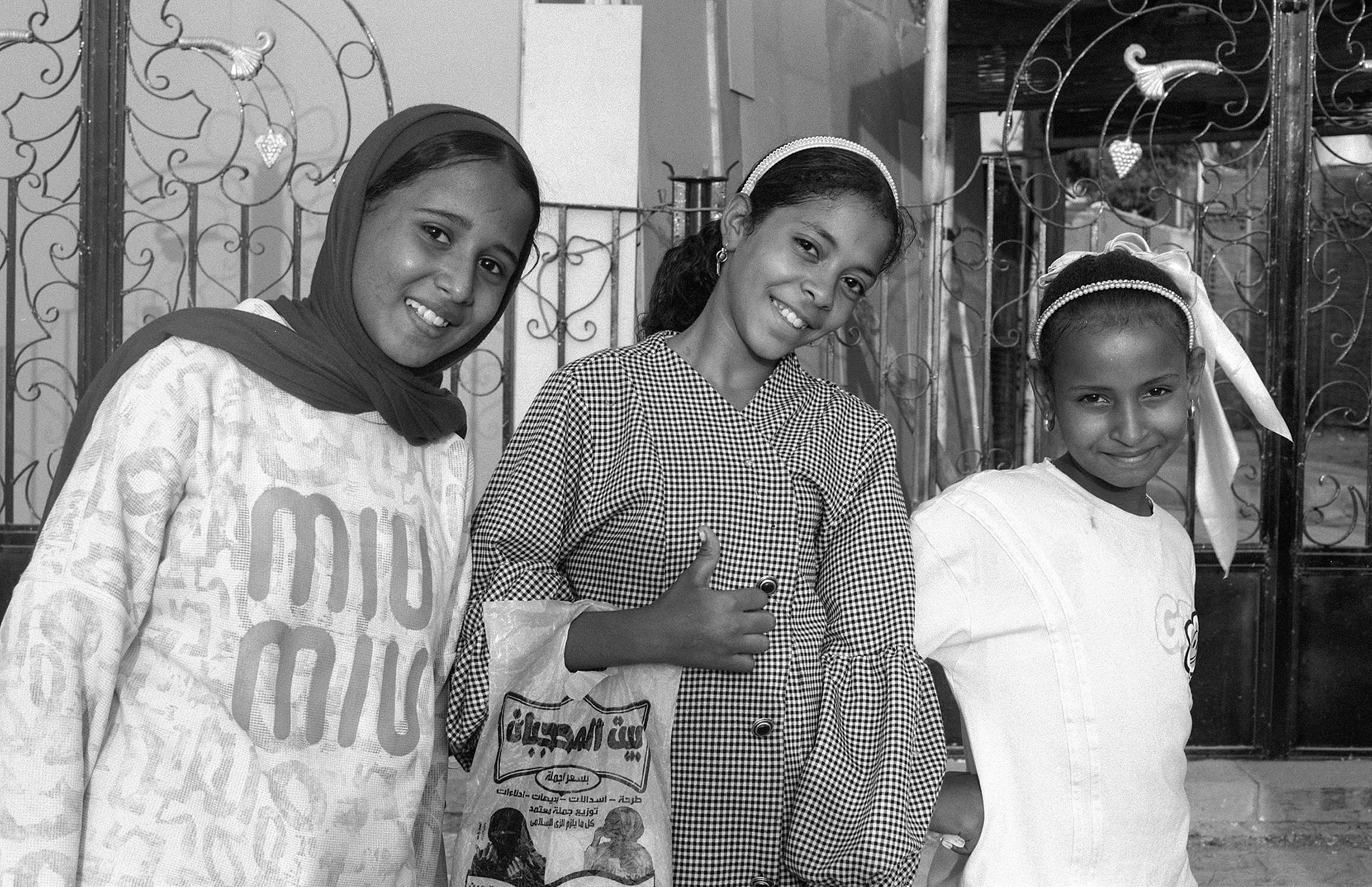 Three girls smiling together outside a home in Egypt