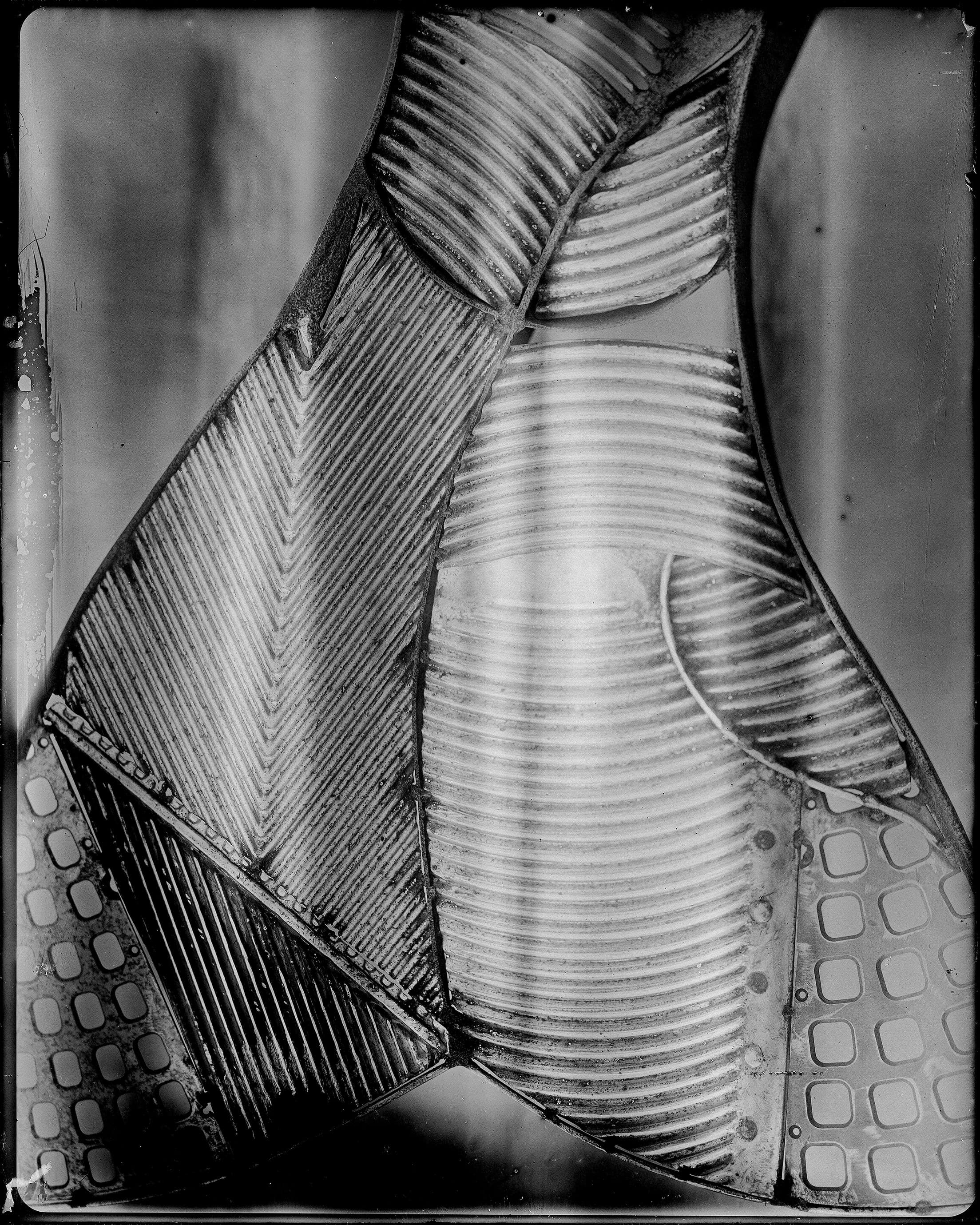 Abstract monochrome close-up of overlapping ribbed industrial forms with repeating perforations