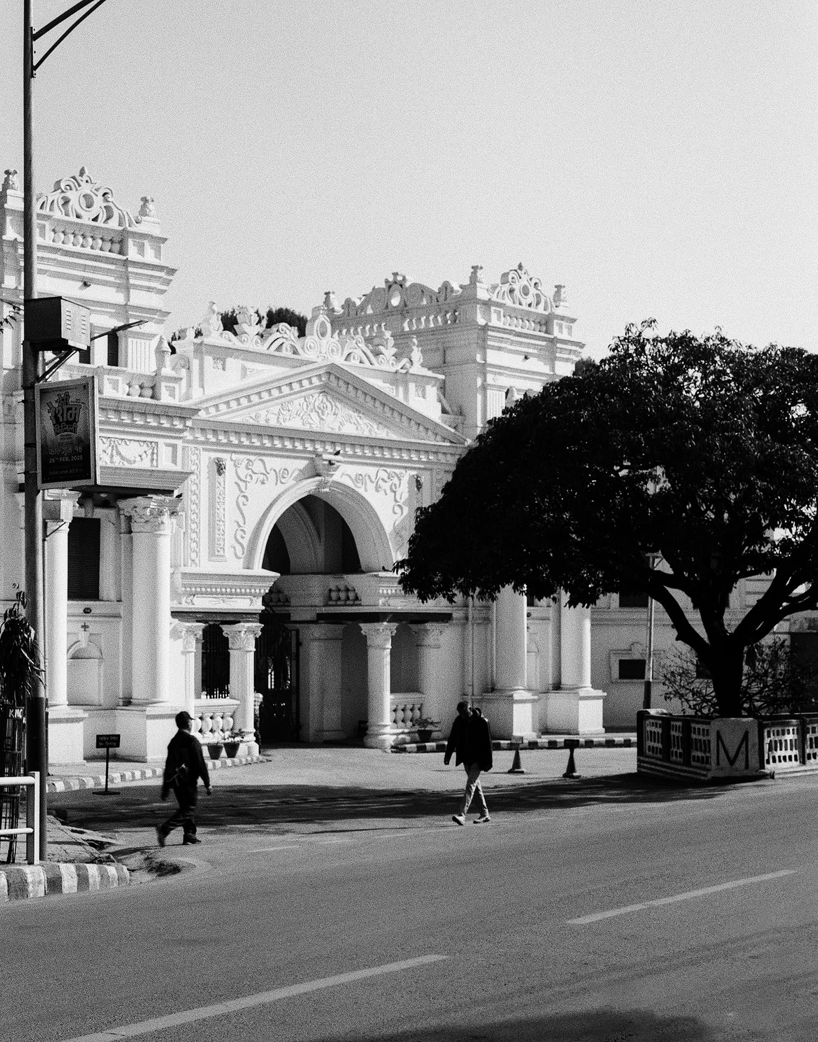 Pedestrians crossing in front of an ornate white palace in Kathmandu