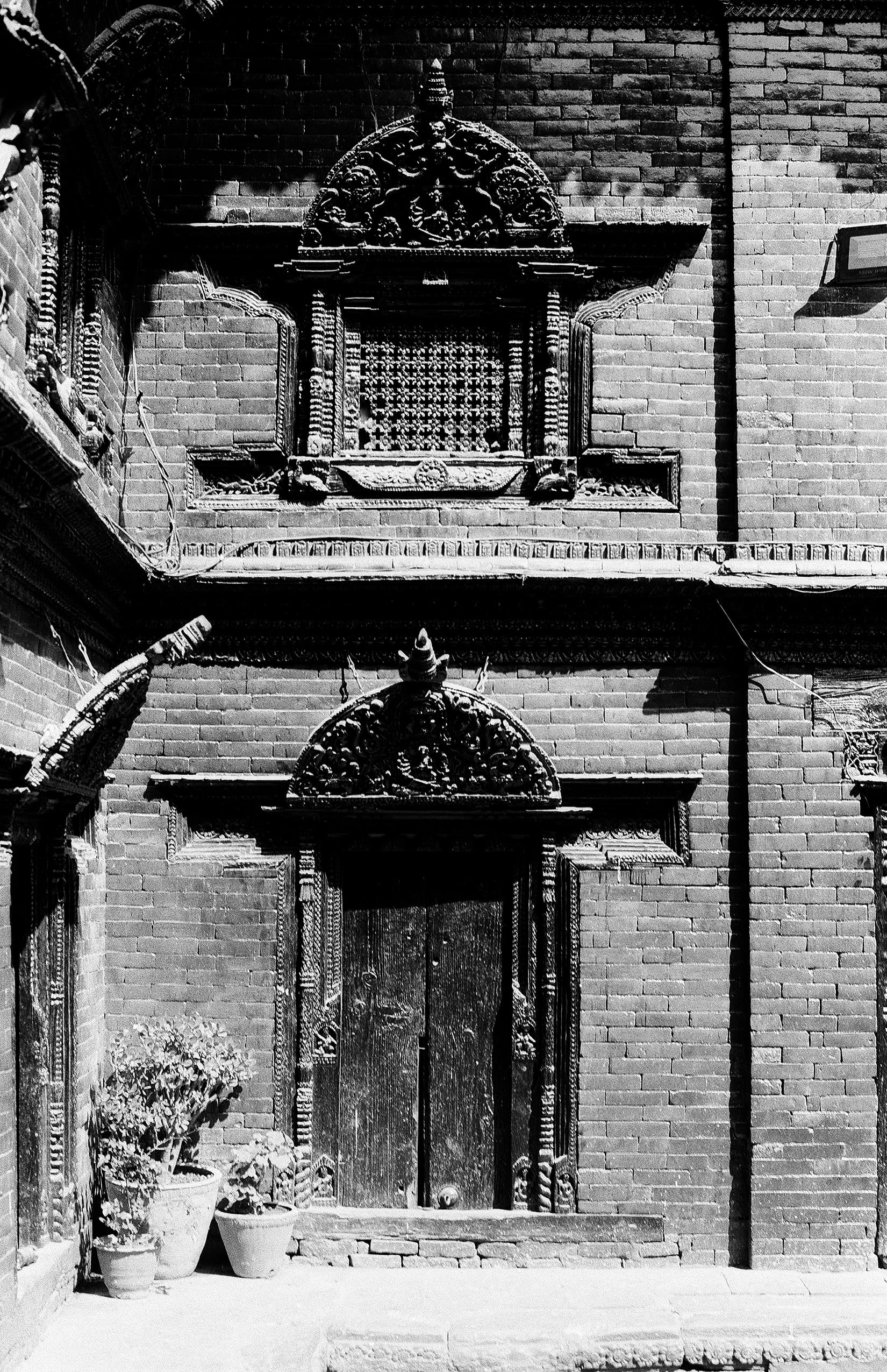 Carved Newari window and doorway set in a brick facade