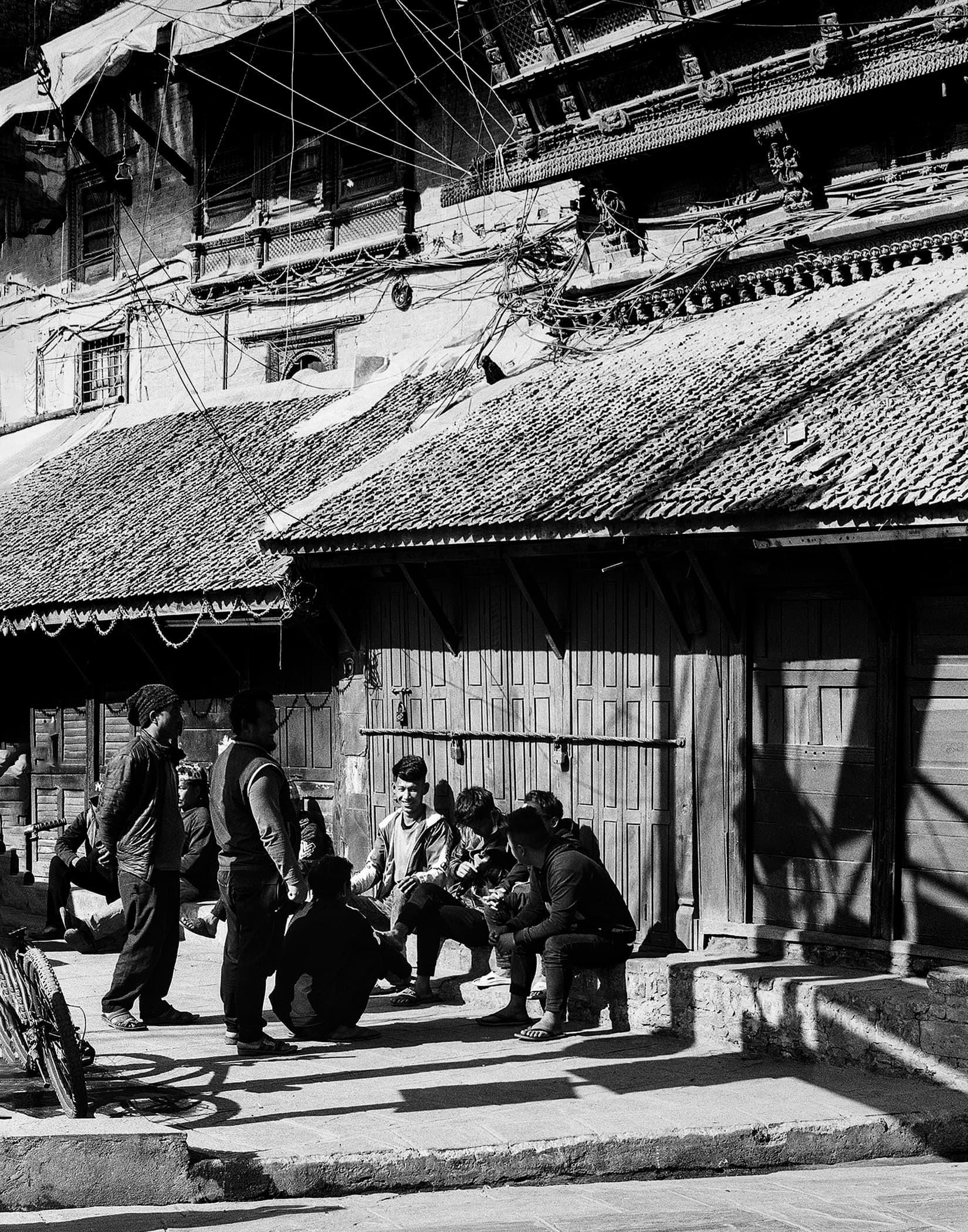 People gathered outside traditional wooden doors beneath tangled wires