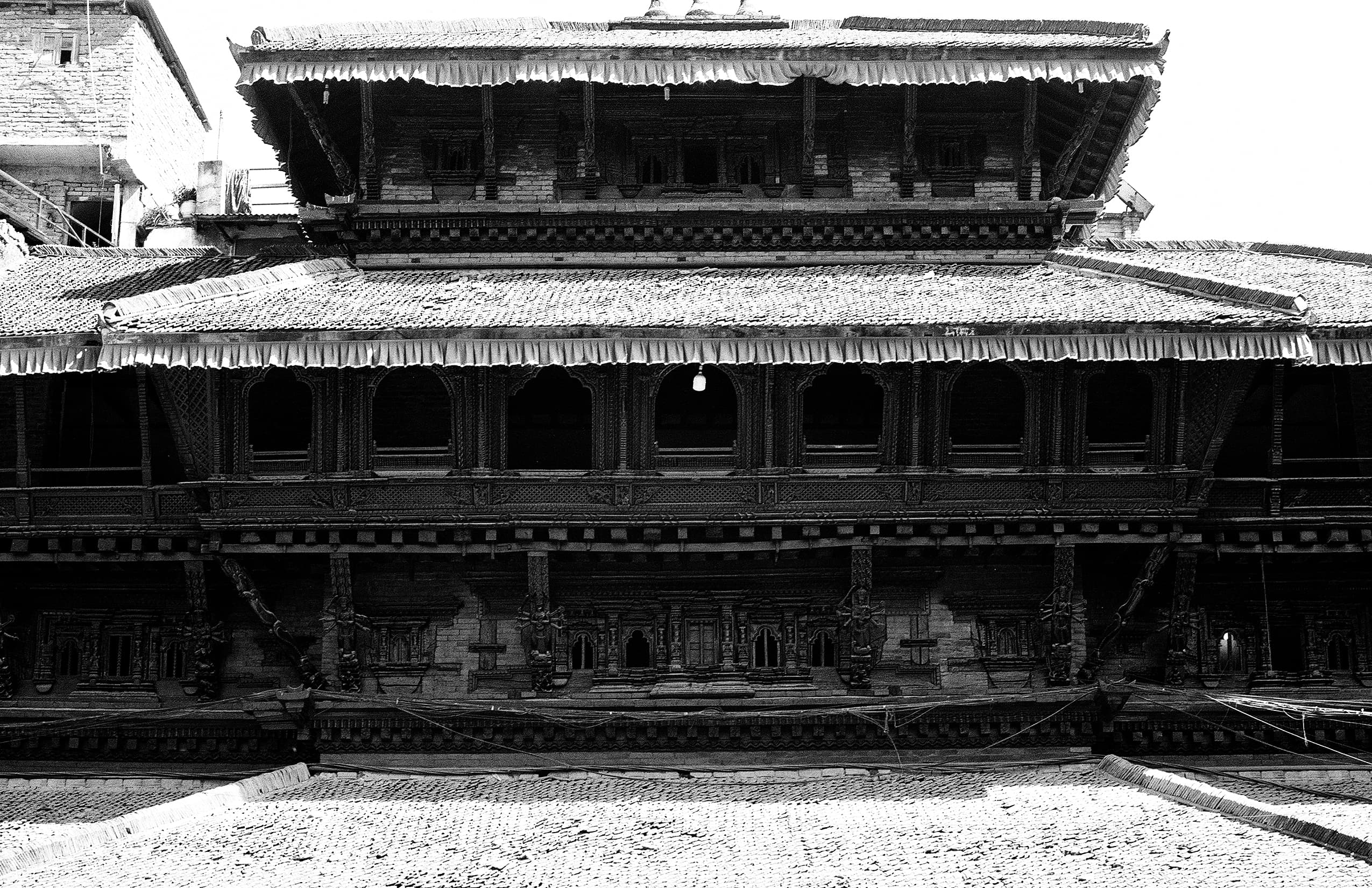 Long traditional Newari building with carved arcades and shuttered windows