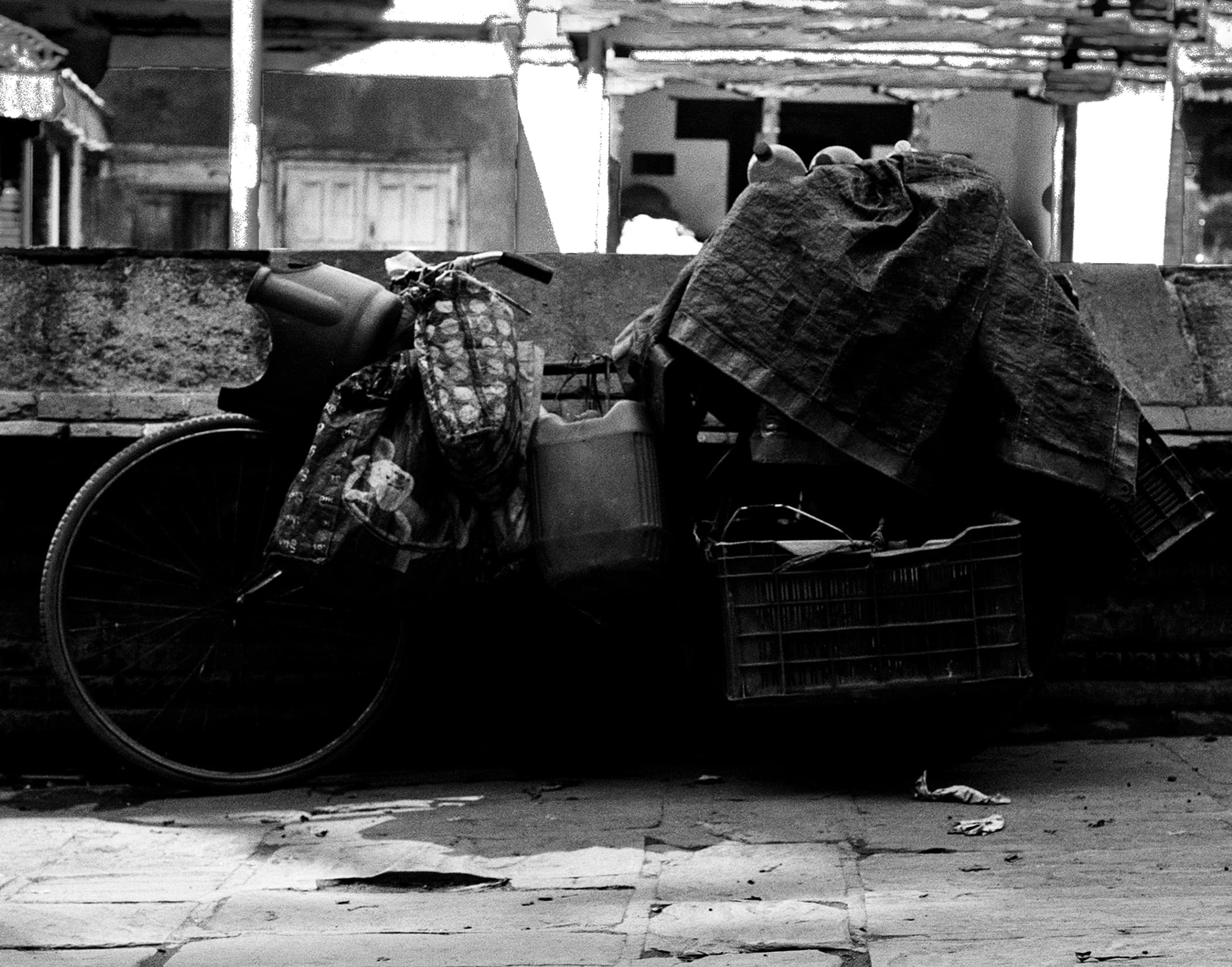 Loaded bicycle and bundled goods resting beside a stone wall