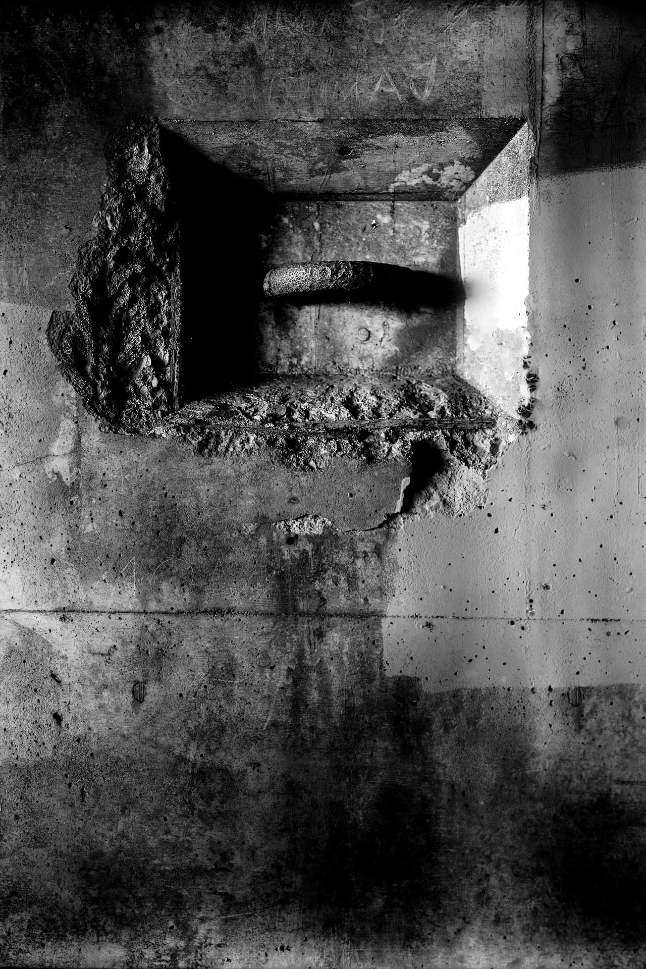Weathered photograph of a rough wall niche with a projecting stone form and chipped plaster