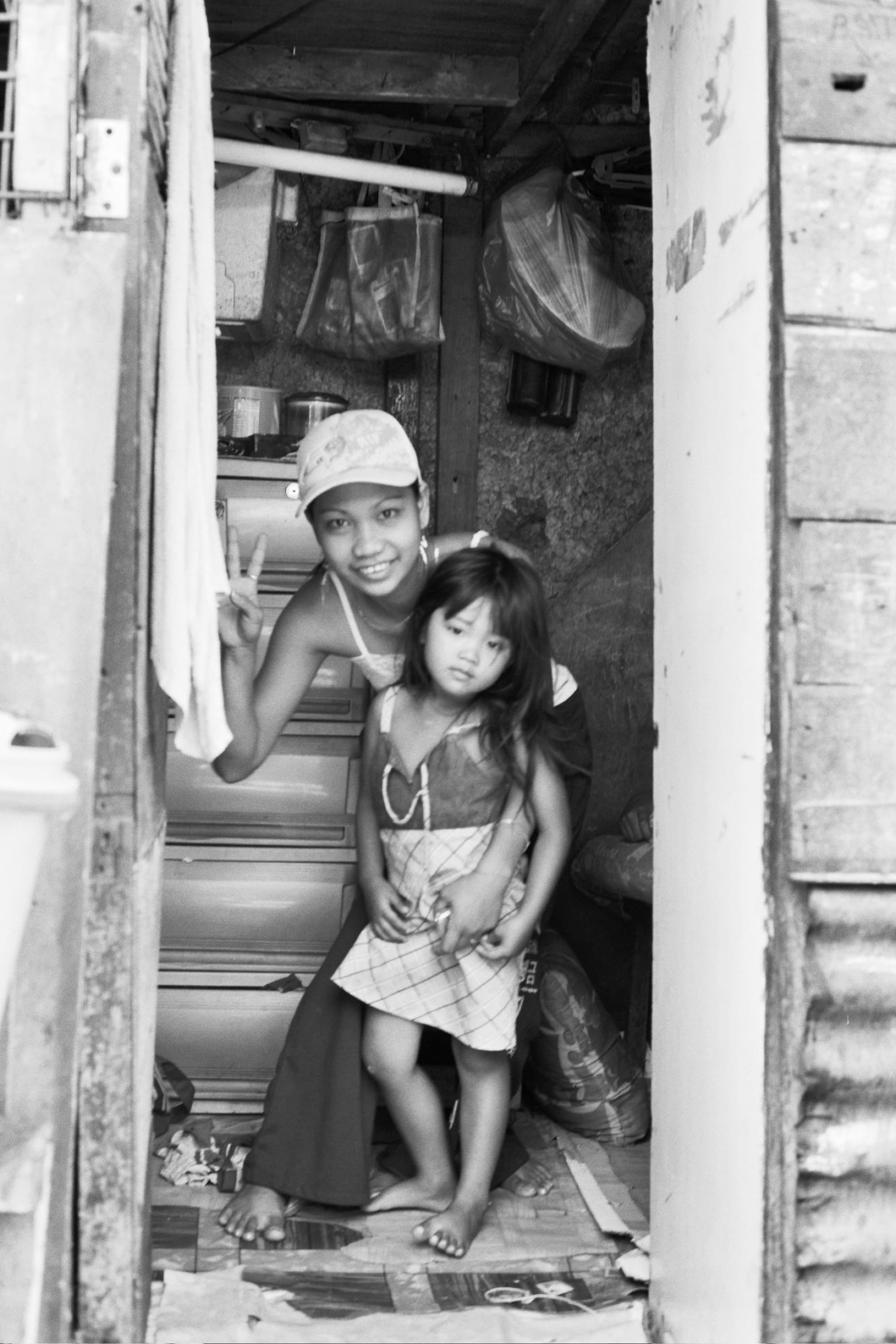 Smiling young woman flashing a peace sign while holding a little girl in a narrow doorway