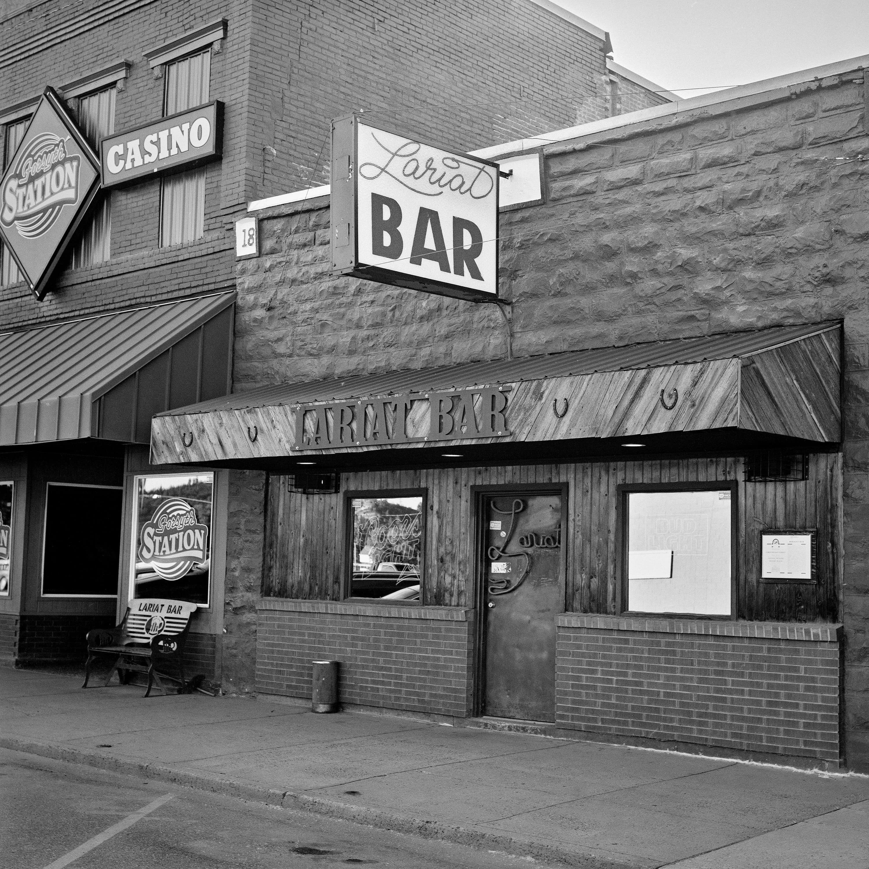 Lariat Bar with vintage neon signage and Forsyth Station casino on small town main street