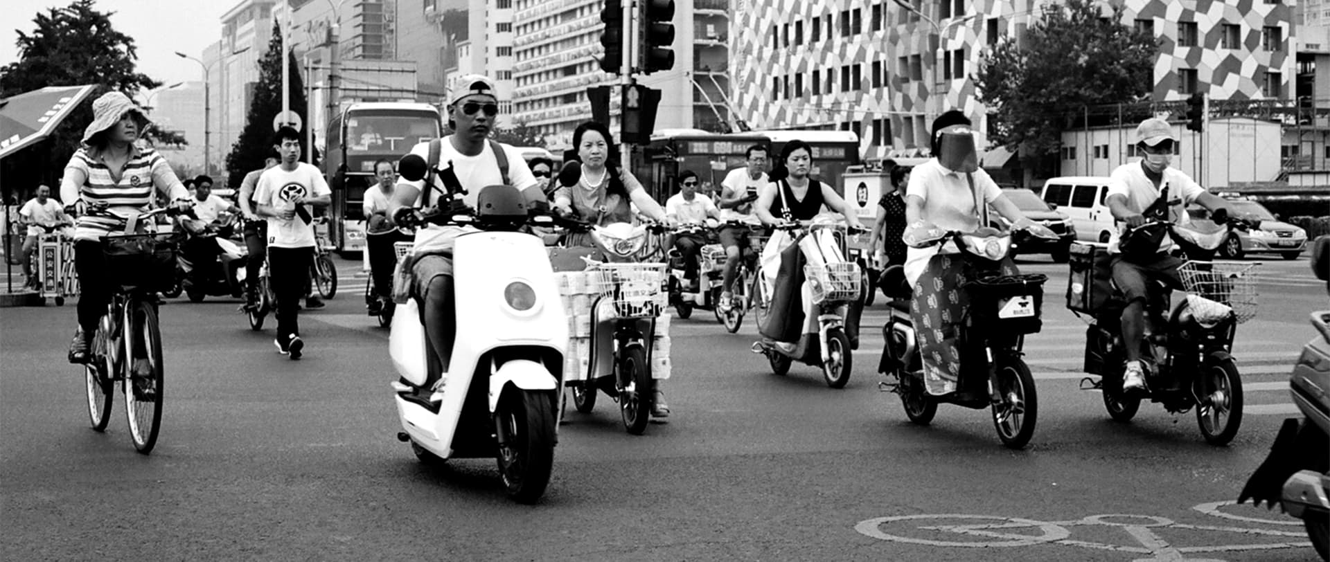 Street scene with people on scooters bicycles and mopeds in busy urban area