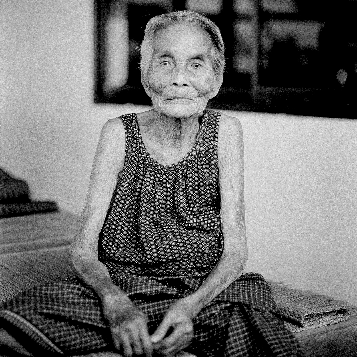 Elderly Thai woman with dignified expression wearing geometric patterned dress